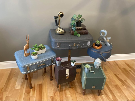 Vintage suitcases have been made into small tables by adding legs. The tables hold objects such as books, telephones, plants and candles.