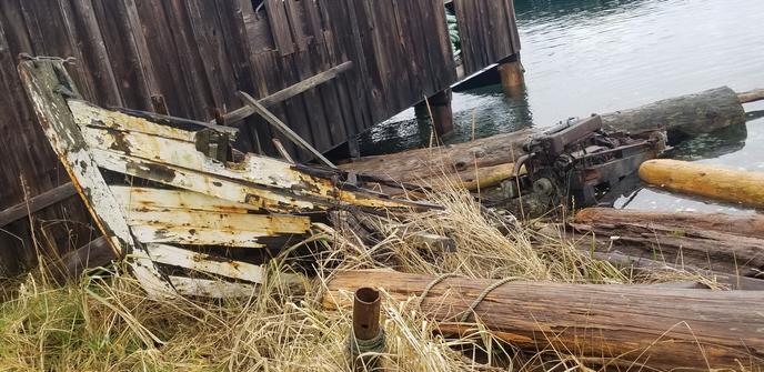 Abandoned, decaying boat shed & old fishing boat wreck on beach.