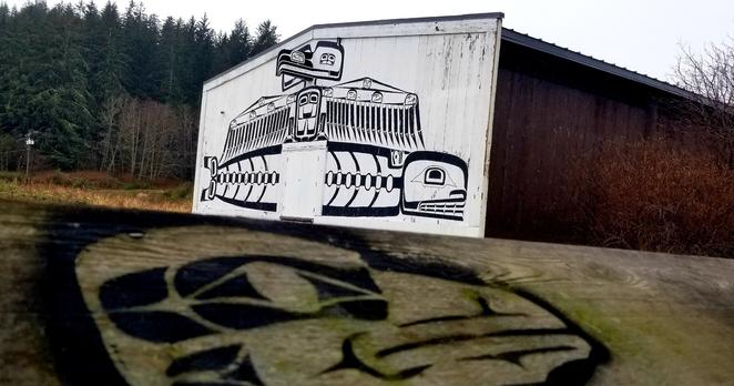 Longhouse at Umista Cultural Center. Viewed from covered viewpoint - with native art in foreground - painted on viewpoint railing.