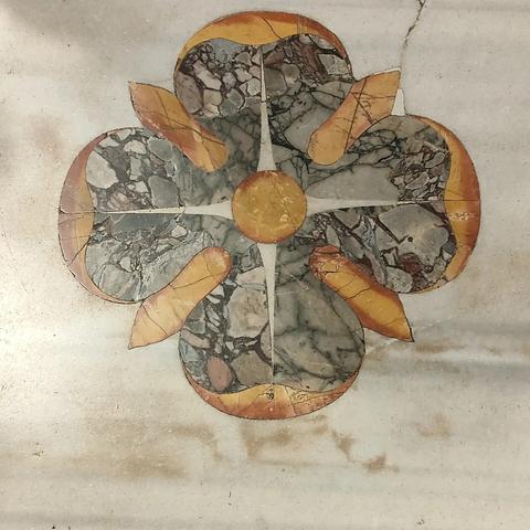 Floor tile from Basilica Papale di Santa Maria Maggiore, Rome. A highly stylized flower with four main petals made of green-grey marble with orange inlaid at the edges