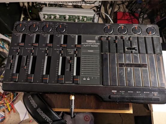 Yamaha MT100 cassette multitracker. A black plastic gadget with multiple sliders and knobs on its surface.