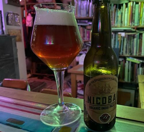 tasting Bierglas mit eingefülltem Bio-India-Pale-Ale und die leere Flasche daneben, beides steht auf der Theke der unmittelBAR.