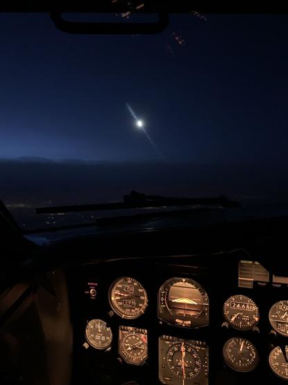 The moon above the cloud layer, seen from the flight-deck of a classic Boeing 737-300. In the foreground are the Captain's analogue instruments.