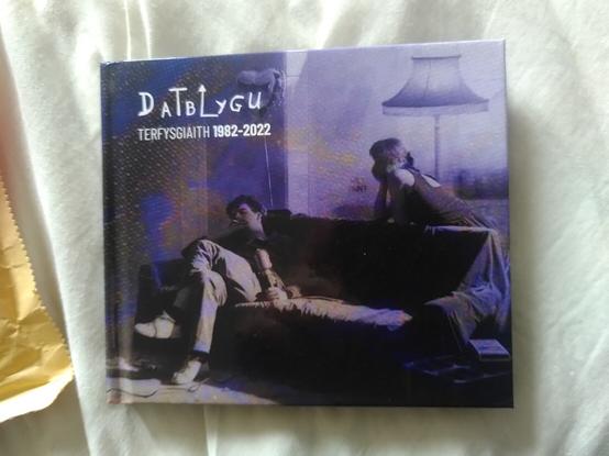 CD case - features a man on a sofa smoking and a woman leaning over the sofa. Text reads 'Datblygu - Terfysgaith 1982-2022