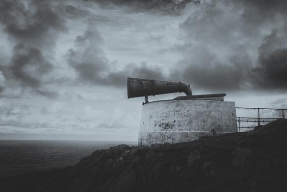 A fog horn atop a cliff at Cape Wrath. A black and white image with darkening skies.