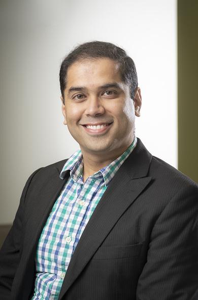 This is a profile picture of Dr. Kantak. He has brown short hair and wears a check shirt in blue, green, white colours and a black jacket. Dr. Kantak is smiling. The background is white.