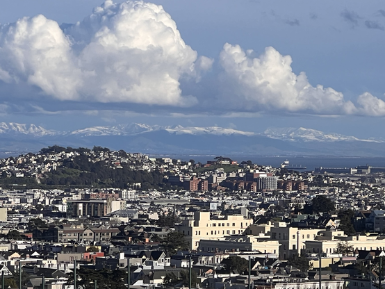 View to the south east from San Francisco. Looking over the city and bay at east bay hills with light snow. Clouds over hills.