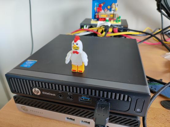 An HP Elitedesk 800 G1 DM on top of a Prodesk 400 G3 DM.
The Elitedesk is powered on and has a lego minifigure standing on its top

An USB cable is plugged in its right front USB port