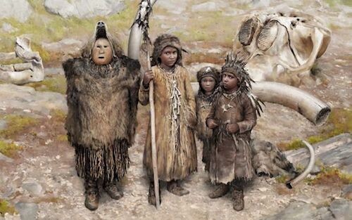 Image via Aeon Magazine: A depiction of 4 Ice Age children dressed in skins and furs. One of the taller ones wears a mask and what looks like a bearskin and headpiece, while the other older child carries a wooden spear. In the background, the huge, bleached skull bone and tusk of a giant animal.