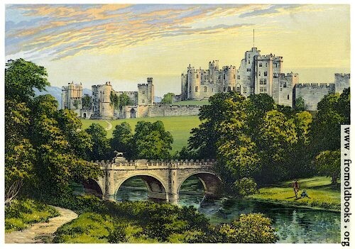 Alnwick castle seen at sunset from the other side of the River Aln. It's large and has multiple distinct buildings. Bridge and trees in foreground.