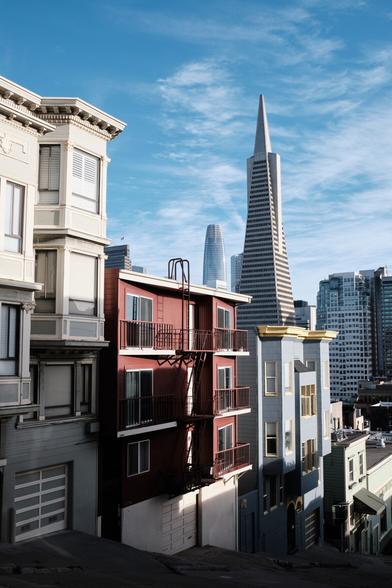The Transamerica Pyramid and Salesforce Tower in San Francisco looming over a mix of old and new buildings on a steep street.
