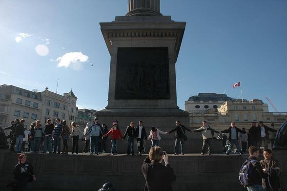 People standing in Trafalgar Square, holding hands in a long line