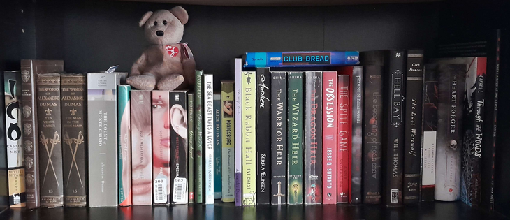 Picture of one of my book shelves. This one contains the books: ICO, Songs of Honor, Ten Years Later, The Man in the Iron Mask, The Count of Monte Cristo, Hebi ni Piasu (localized in English as "Snakes and Earrings"), the Uglies Trilogy, Green Angel, Green Witch, The Sea Beast Takes A Lover, Water Tales, The Outcasts of 19 Schuyler Place, The Wolf Leader, Black Rabbit Hall, Awoken, The Heir Trilogy, The Obsession, The Spite Game, Pictures of Hollis Woods, The Becoming of Noah Shaw, Hell Bay, The Last Werewolf, The Vampyre and Other Tales, Kizumonogatari, The Heart Forger, Through the Woods and When I Arrived at the Castle. My copy of Club Dread also sits on top of some of the other books. Why is it up there? It's one of my favorite books and I wanted it to have a place to sit while I cleaned my other shelves!