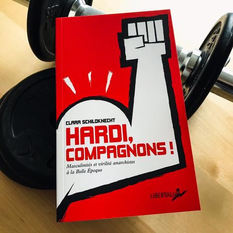 Photo du livre posé sur des haltères. Couverture du livre : un poing levé qui fait gonfler un biceps.