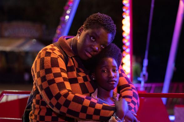 A beautifully lit image from Girl, in which mum and daughter are bathed in light from a fairground ride.