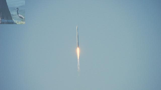 A photograph of an Atlas 5 rocket and its exhaust flame against the blue sky.