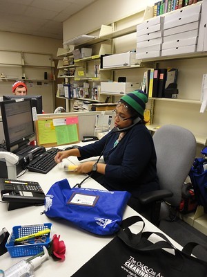 library staff working at desks on computers and talking on the phone surrounded by interlibrary loan envelopes and boxes