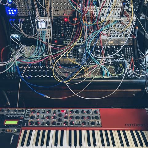 Studio shot. A large modular synth with a keyboard synth in front
