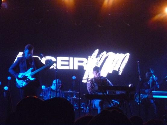 Asgeir seated at a keyboard singing on stage with 3 band members around him.