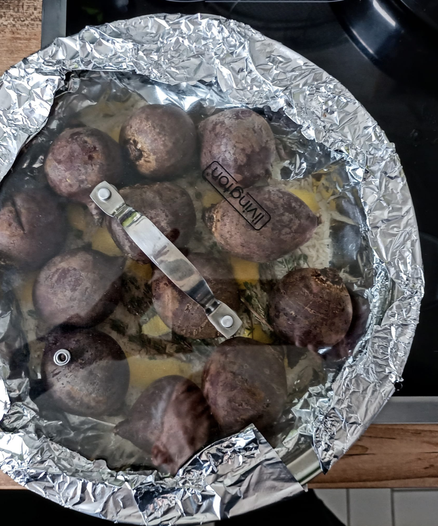 Auf der Pfanne ist jetzt ein Deckel und die überstehende Alufolie wurde über den Deckel gefaltet und fest gedrückt. Durch den Glasdeckel sieht man die Rote Bete in der Pfanne liegen.