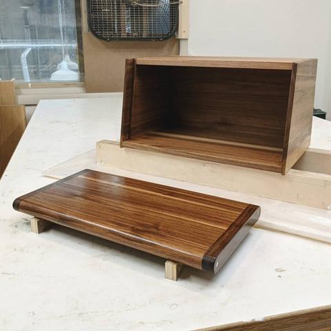 A walnut bread box and cutting board drying after applying a polyurethane finish.