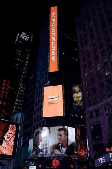Time Square display of orange signage for the National Multiple Sclerosis Society and the hashtag WeAreStrongerThanMS.org

MS happens when one’s own immune system mistakenly attacks the coating on the nerve fibers in the central nervous system. 

Imagine the white waxy coating on your phone’s charging cable, then imagine rodents nibbling most of it away in spots, exposing the wires inside that conduct signals. 

You end up replacing that cable because it’s not working right anymore. 
These signals are the communication we rely upon for organ function, muscle movement, executive function, sleep, basic drives like hunger… nothing happens in the body without a signal exchange between the central nervous system and the body. 

As you might imagine, in MS, those signals are either erratic/unreliably conducted or fail to conduct at all. 
That is MS… and every case is different depending upon the damage inflicted. 
2 million people in the United States have MS. 

There is no cure for MS and researchers still can’t agree on what causes it to happen in the first place. 
But we all still have to live with it, and that includes dealing with pain, fatigue, and bodies and brains that don’t work the way they’re supposed to. 

Sadly, we cannot replace brain cells, so those with MS have to live with broken brains.

Or in some cases, we succumb to this disease. I literally lost a goddaughter to MS _just last week_  SHE WAS 36 YEARS OLD.