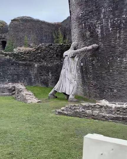 A screenshot of a statute holding a leaning tower