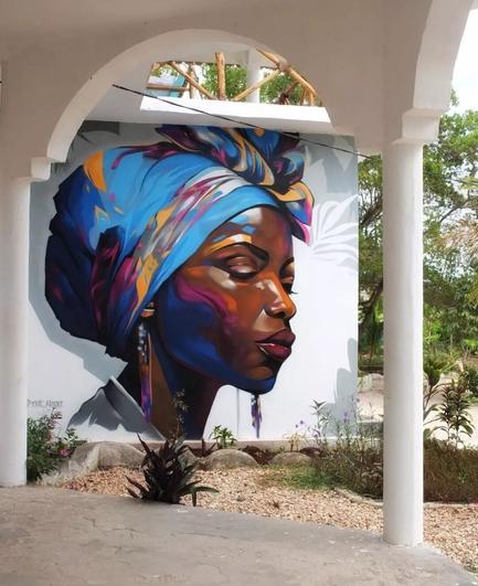 Streetartwall. On a white outer wall of a hotel in Zanzibar is sprayed / painted a wonderful portrait of a black woman with a blue cloth turban.