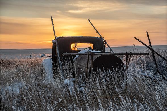 A wrecked and abandoned 1930s truck faces the sunset on the High Plains