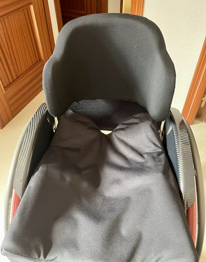 Silla de ruedas negra donde se ve el espaldar