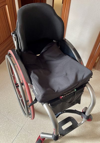 Silla de ruedas negra donde se ve el espaldar