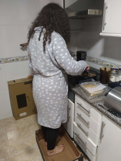 katey cooking mushrooms in the kitchen. she is standing in a cardboard box