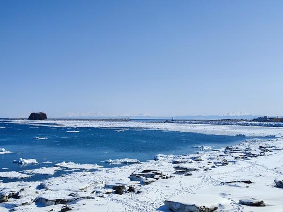 Snowy Abashiri coast with the Shiretoko Peninsula visible in the background