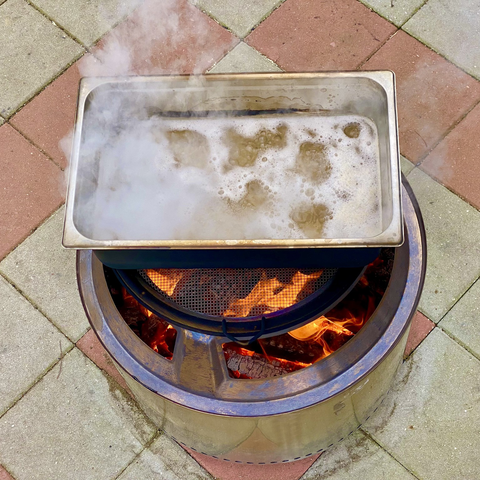 A pan of maple sap boils above a Solo stove’s wood fire.