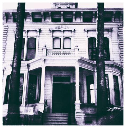 John Muir house on the national historic site. The camera is facing the front of the house, looking up the stairs and into the open front door. A faint purple tinge has been applied to the image with a filter, and the contrast between lights and darks has been enhanced.