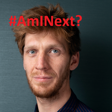 headshot with the text #AmINext? written in red font.