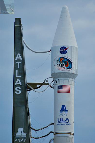 A United Launch Alliance Atlas 5 rocket’s 4 meter fairing with the Radiation Belt Storm Probes, a NASA logo, United States flag, and Atlas logo.