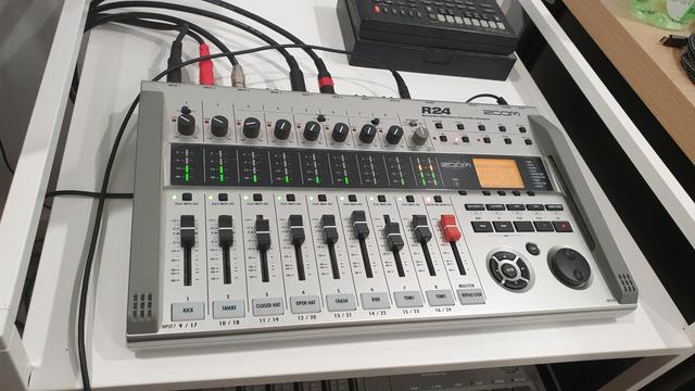 A Zoom R24 multi-track recorder with the playback and record icons illuminated.

All track status icons are green, the master track status is red.

The volume indicators for each channel are of varying levels but all 8 are active.