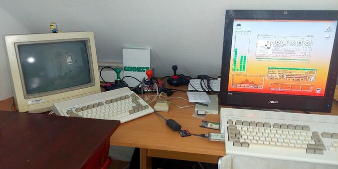 Amiga 600 mit Maus und Comodore 1085S-Monitor auf dem eine kleine Minionfigur steht, Box des neuen Amiga-Knobelspiel "CONNECT", mehrere Joysticks, RaspberryPI 400, externes Amiga-Diskettenlaufwerk, Amiga 1200 mit PCMCIA-Netzwerkkarte und 19-Zoll-TFT