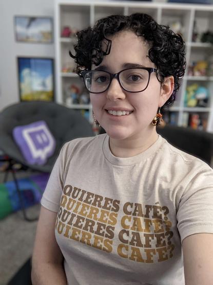 Fierce in their streaming room wearing a beige shirt that says "Quieres Cafe?" four times in brown text.