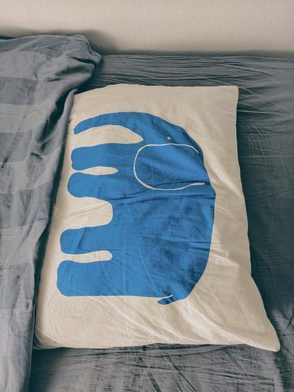 A bed with a pillow on top that has an image of an elephant.