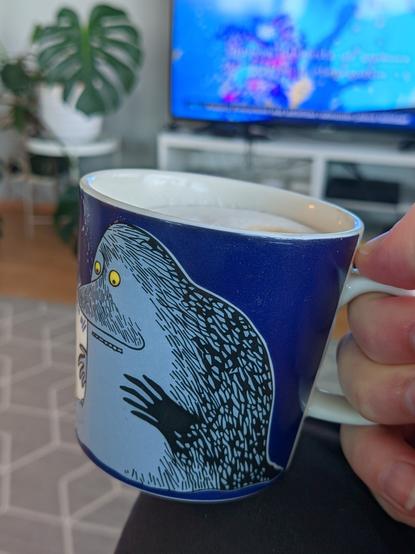 Mörkömukissa kahvia, taustalla Ylen aamun sää telkkarissa ja peikonlehti.
