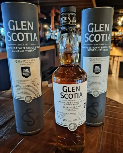 Op de voorgrond op een houten tafel de festivalbotteling van het Whisky Weekend Twente, een Glen Scotia Campbeltown single malt whisky 5yo. Exclusive cask, first fill Oloroso Hogshead cask. 
Verdere tekst op het etiket: mooi dai der warn. Good goan!

Links en rechts naast de fles twee whiskybussen van de Glen Scotia, antracietkleur met crèmekleurige etiketten en bedrukking.