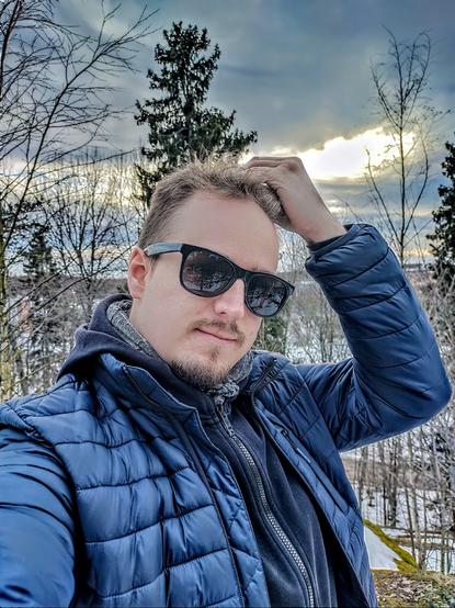 A selfie of a man in sunglasses with an electric blue jacket.