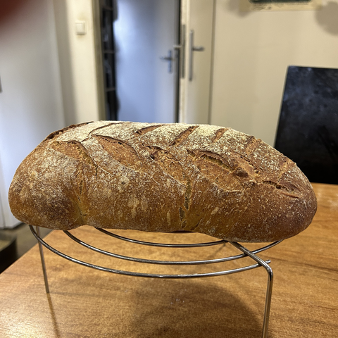 Closeup of the bread, still on its rack, from the side. This shows that the bread has risen well. It also shows of part of that leaf pattern nicely.