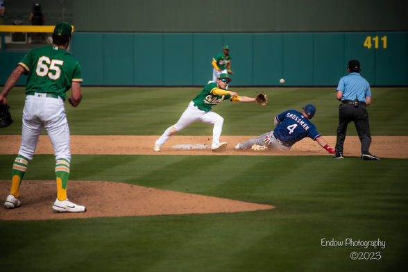 Oakland A’s shortstop Nick Allen tries to catch an errant throw at second base from the the catcher, while Texas Rangers outfielder Robbie Grossman slides safely into the base.
