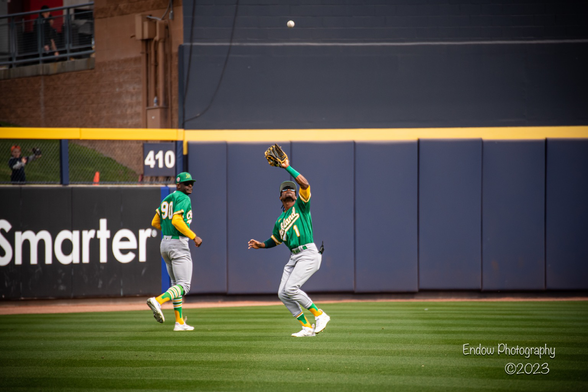Oakland A’s outfielder Esteury Ruiz tracks a fly ball into his glove as teammate Denzel Clarke backs up the play