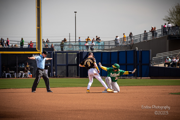 Oakland A’s catcher Yohel Pozo sits on the base after safely sliding into 2nd for a double. Both he and the umpire simultaneously make a safe gesture with their arms, while San Diego Padre Jake Cronenworth stands with his right foot on the base