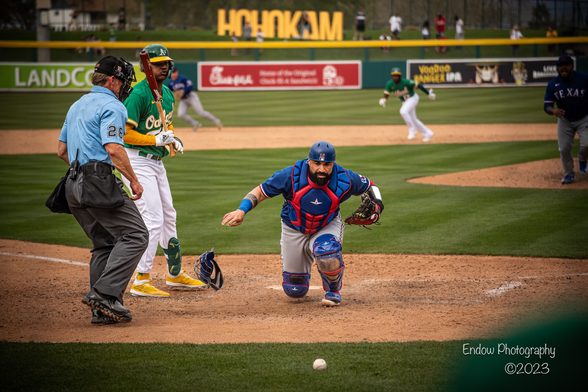 Texas Rangers catcher Sandy Leon throws away his mask and turns to the backstop and chases down the ball after a pitch got past him. Oakland A’s batter Christian Pache stands with his bat in the batters box and watches the play unfold