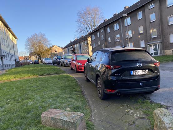 Ein typischer Gehweg mit drauf geparkten Fahrzeugen